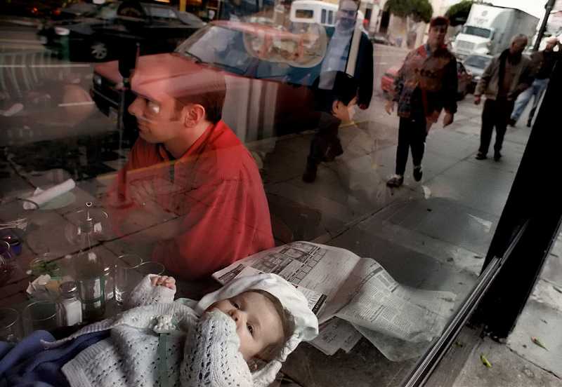 Parents Darrell Reimer and his wife Beth Jost-Reimer (not shown-out of picture) of Toronto, Canada, talk as their newborn 2-month-old baby, Lucy, lays comfortable in the window sill and takes in the sights of people walking by  safely above their table at The Stinking Rose Garlic Restaurant on Columbus in North Beach of San Francisco. 1/19/99Examiner/Darryl Bush